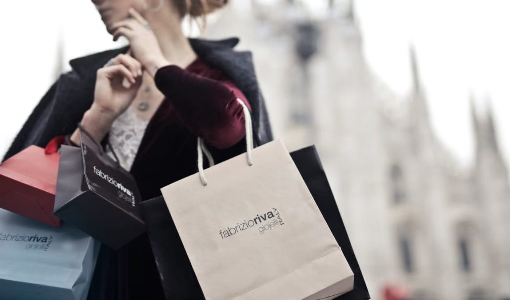 Stylish woman holding designer shopping bags near Milan's iconic Duomo. Urban fashion and lifestyle concept.