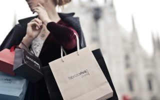 Stylish woman holding designer shopping bags near Milan's iconic Duomo. Urban fashion and lifestyle concept.