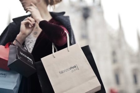 Stylish woman holding designer shopping bags near Milan's iconic Duomo. Urban fashion and lifestyle concept.