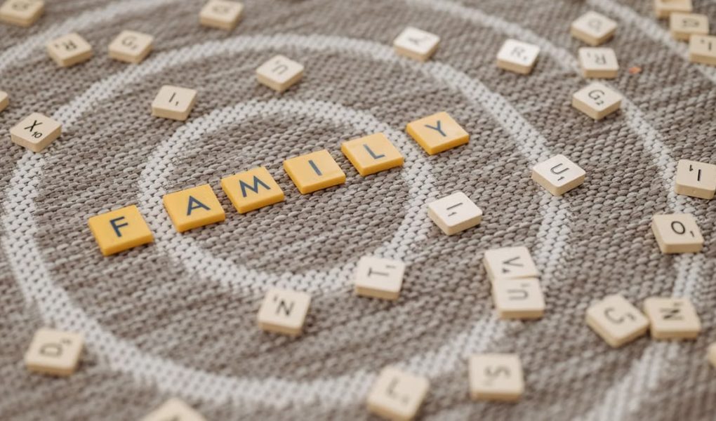 An artistic display of Scrabble tiles spelling 'FAMILY' on a textured carpet surface.