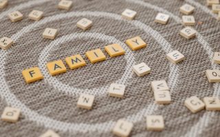 An artistic display of Scrabble tiles spelling 'FAMILY' on a textured carpet surface.