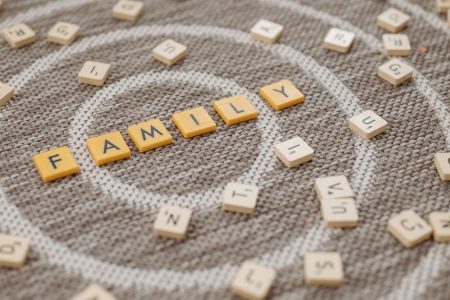 An artistic display of Scrabble tiles spelling 'FAMILY' on a textured carpet surface.